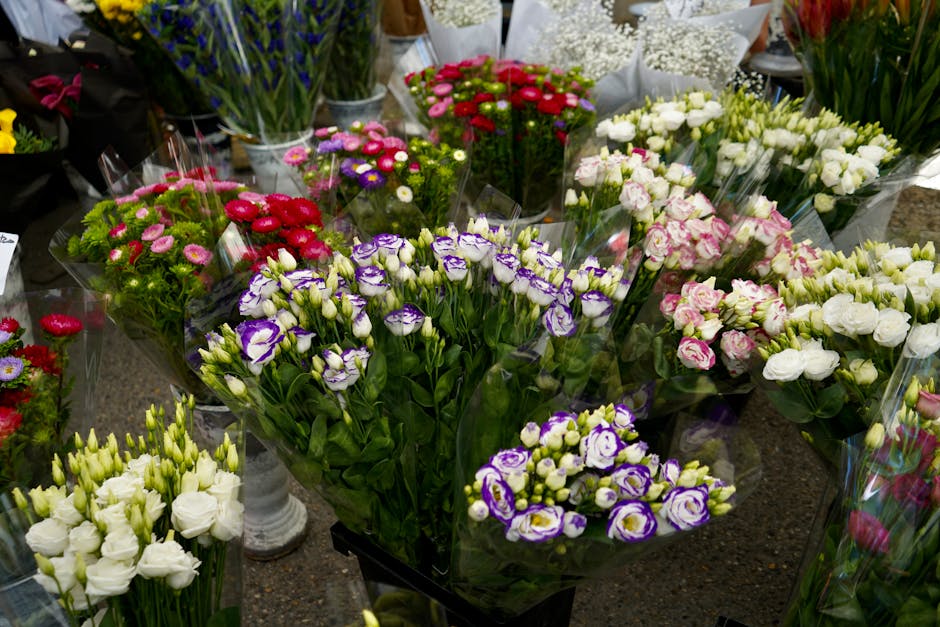A vibrant display of fresh flower bouquets arranged on a table outside a flower shop, featuring a variety of blooms including purple and white lisianthus, pink and white roses, red and pink daisies, a